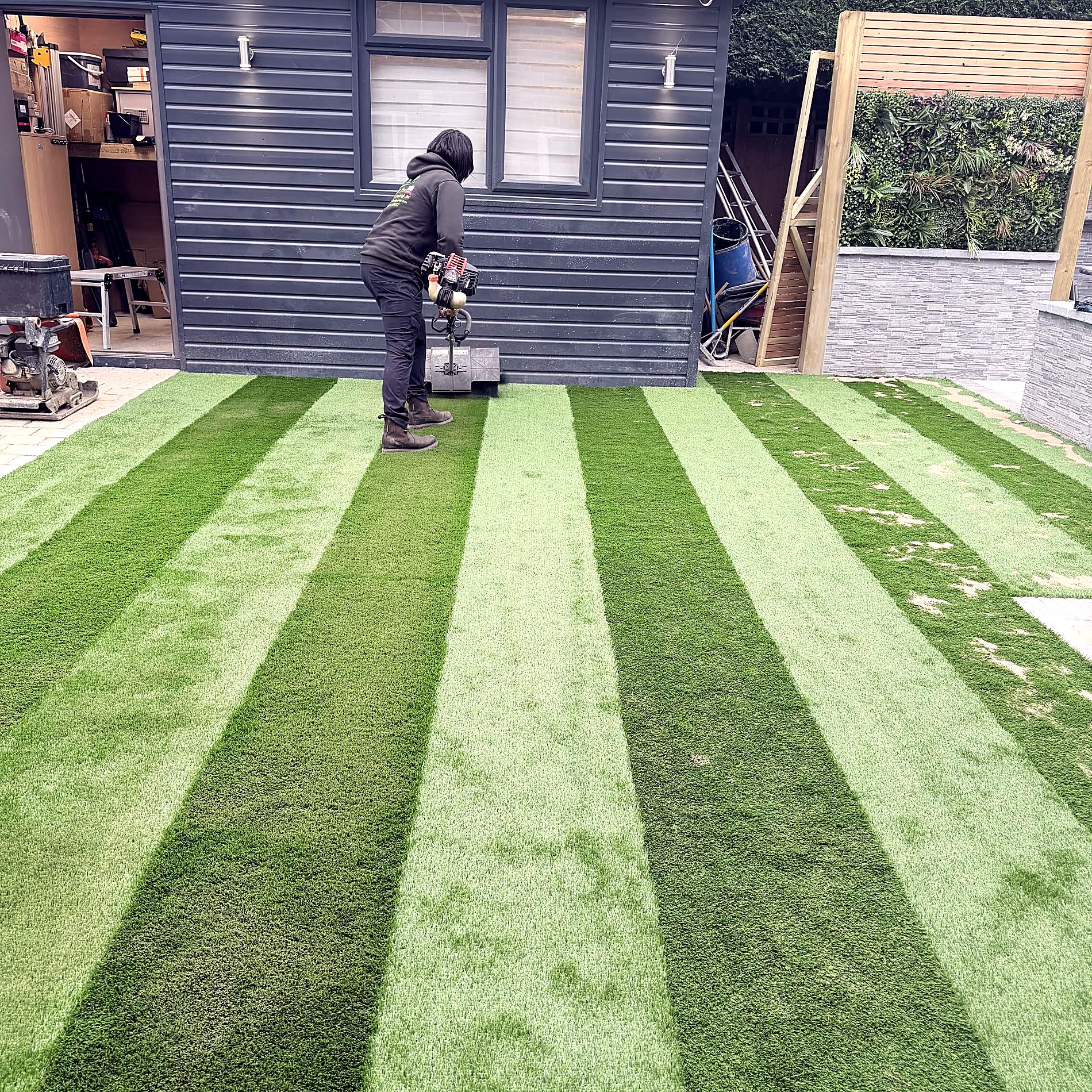 New turf laid to a stripe, framed by a curved patio edge.